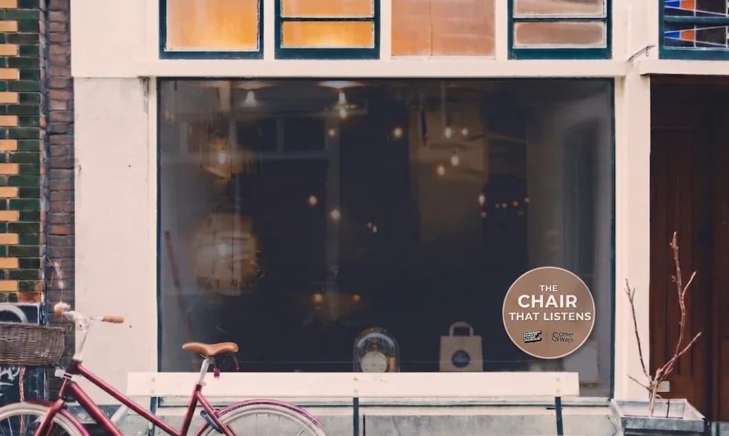 A barbershop storefront with a The Chair That Listens sticker in the window.